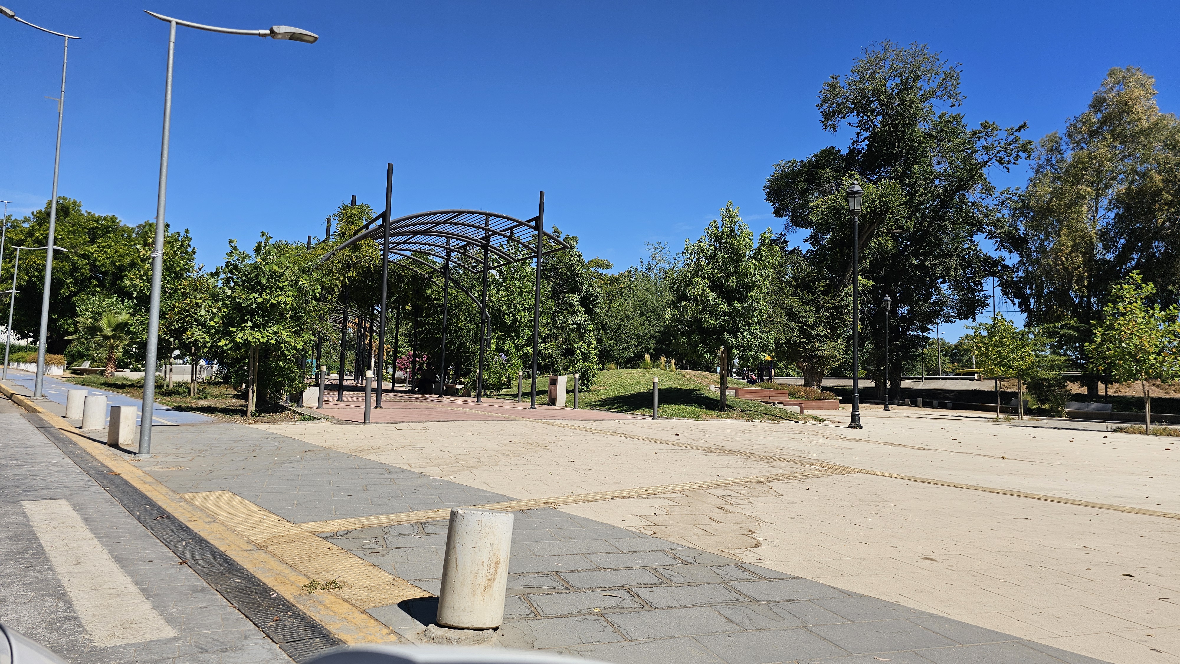 Fotografía de un sector amplio del parque con 2 senderos que cuentan con pisos podotáctiles y árboles por el costado